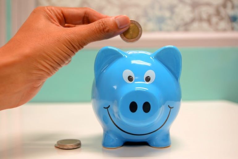 A person is putting a coin into a piggy bank